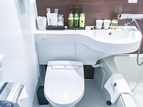 a bathroom with a white toilet and a sink at HOTEL LiVEMAX Nagoya Sakuradoriguchi in Nagoya