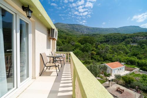 einen Balkon mit einem Tisch, Stühlen und Bergen in der Unterkunft Guest House Ana in Petrovac na Moru