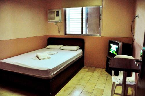 GV Hotel - Ipil في Ipil: غرفة نوم بسرير وتلفزيون ونافذة