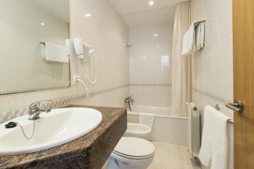 a bathroom with a sink and a toilet and a tub at Hotel Alta Garrotxa in Tortellá