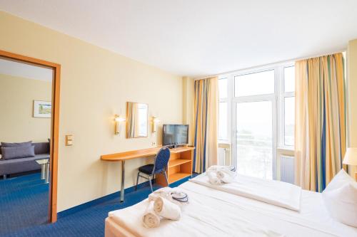 a hotel room with two beds and a desk at Arkona Strandhotel in Binz