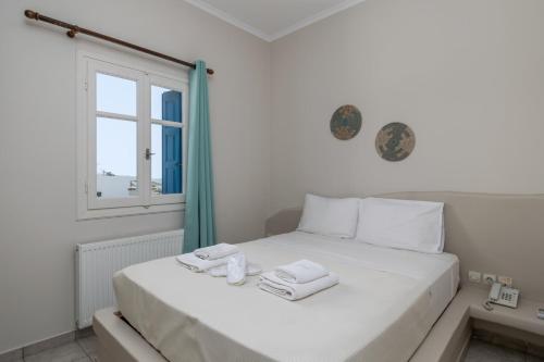 a bedroom with a white bed with towels on it at Vira Vivere Houses in Plaka Milou