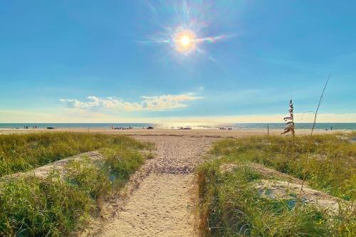 een onverharde weg die naar een strand met de zon leidt bij Sunset Vistas Condo 203S in St Pete Beach