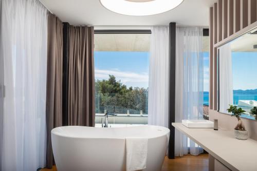 a bathroom with a white tub and a large window at Villa Acacia in Petrcane