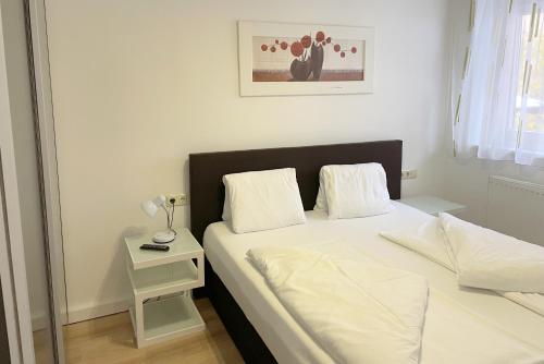 a bedroom with a white bed and a night stand at Areit Apartments - Low Budget in Zell am See