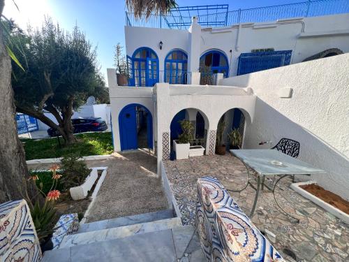 a house with a table and chairs in front of it at OLIVIA Guest House (Eya & Abbes) in Sidi Bou Saïd