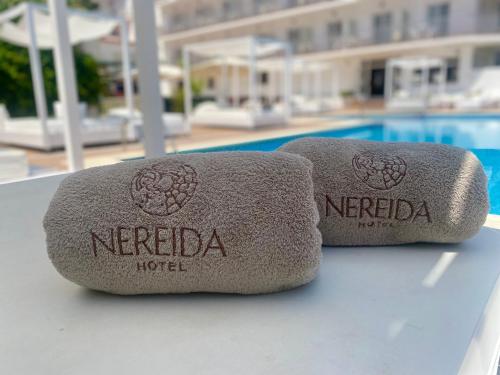 two towels sitting on a table next to a pool at Hotel Nereida in L'Estartit