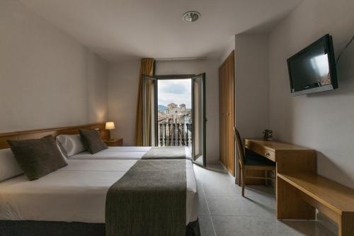 a hotel room with two beds and a television at Hotel Alta Garrotxa in Tortellá