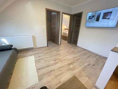 a living room with a couch and wooden floors at Kukorica Csárda Apartman in Balatonújlak