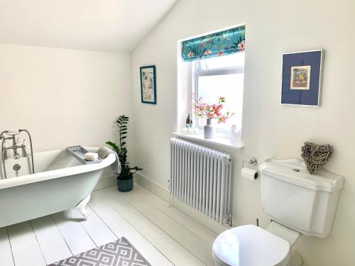 a bathroom with a tub and a toilet and a window at Lovely 3 bed house in the heart of Cheltenham in Cheltenham
