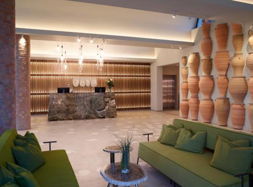 a lobby with a green couch and vases on the wall at Cayo Exclusive Resort & Spa in Elounda