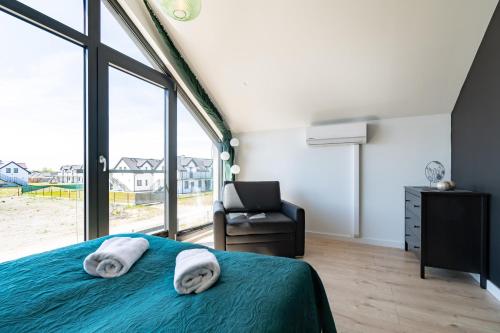 a bedroom with a bed and a chair and a window at Domki - Bursztynova 13 in Łeba