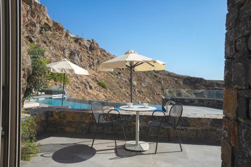 a table and chairs with an umbrella and a pool at panorama new generation in Sfakia