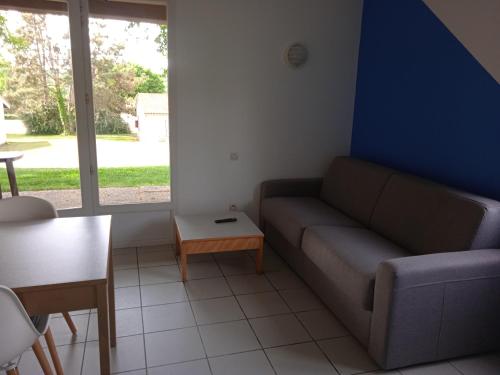a living room with a couch and a table at Olydea le Lambon - Prailles-la-Couarde in Prailles