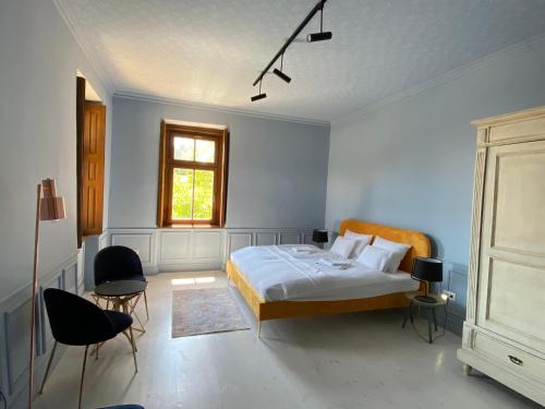 a bedroom with a bed and two chairs and a window at Segesdy Villa in Balatonalmádi