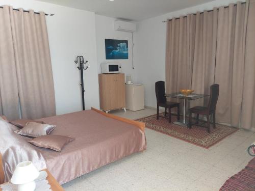 Schlafzimmer mit einem Bett, einem Tisch und Stühlen in der Unterkunft Chambre Hannon Résidence Chahrazad in Sfax