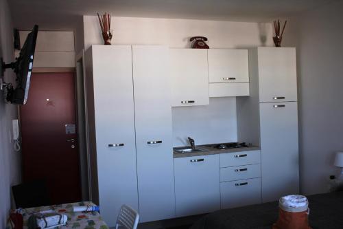 una cucina con armadi bianchi e lavandino di Rosato 3 Sea View Apartment a Lignano Sabbiadoro