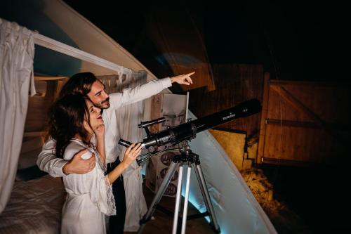 Un uomo e una donna in piedi accanto a una telecamera di Burbujas Astronómicas Albarari Sanxenxo a Sanxenxo