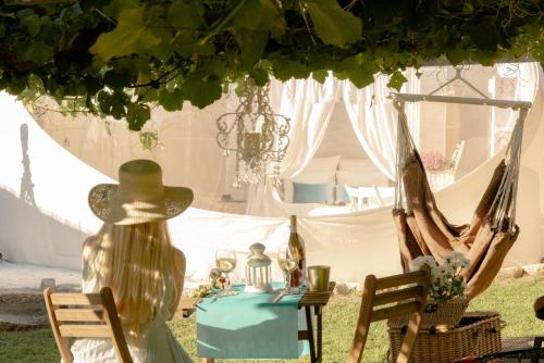 a woman in a hat sitting in front of a tent at Burbujas Astronómicas Albarari Sanxenxo in Sanxenxo