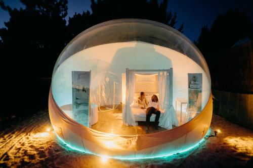 Una novia y un novio sentados en una bola de cristal en Burbujas Astronómicas Albarari Sanxenxo, en Sanxenxo