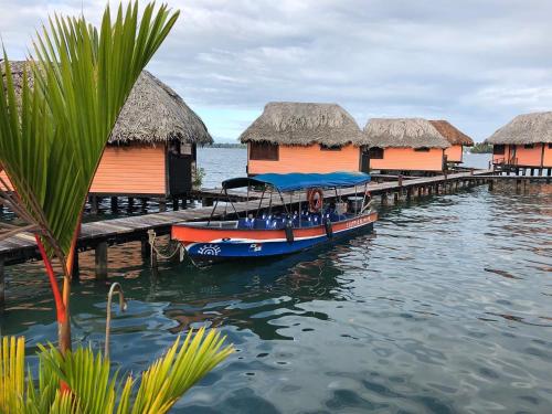 a boat is docked next to a pier with huts at Eclypse de Mar Acqua Lodge in Bastimentos
