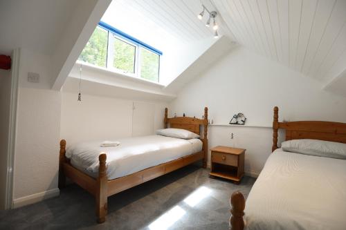 - une chambre mansardée avec 2 lits et une fenêtre dans l'établissement Lyn View Cottage - Modern Lynmouth Townhouse, à Lynmouth