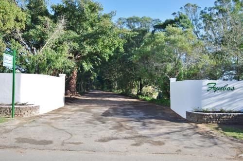 
a small white house with trees and a fence at Fynbos Guest House Riversdale in Riversdale
