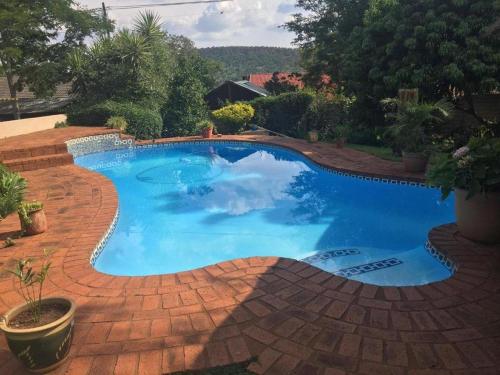 a large blue swimming pool on a brick patio at Meraki Upmarket Guesthouse in Rustenburg