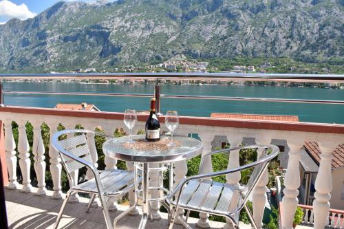 a table with a bottle of wine and chairs on a balcony at Apartments Simun in Kotor