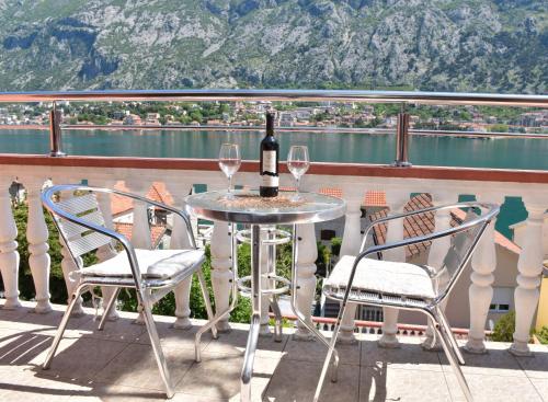 a table with two chairs and a bottle of wine on a balcony at Apartments Simun in Kotor