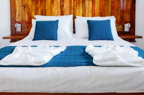 a bed with blue pillows and white towels on it at Le Be-Mahot - Hell Bourg in Salazie