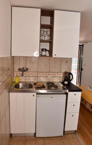 a kitchen with white cabinets and a sink at Apartments Simun in Kotor