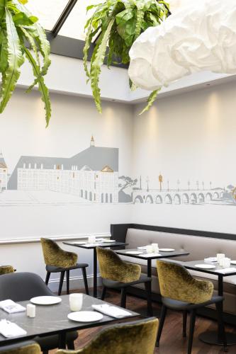 a dining room with tables and chairs and plants at Villas Foch Boutique Hotel & Spa Bordeaux in Bordeaux