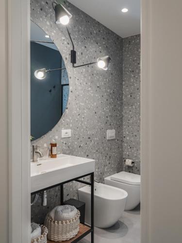 a bathroom with a sink and a mirror and a toilet at Living u HomeSuites in Lecce