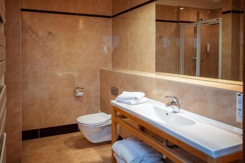 ein Badezimmer mit einem Waschbecken, einem WC und einem Spiegel in der Unterkunft Hotel Kuracyjny Spa & Wellness in Gdynia