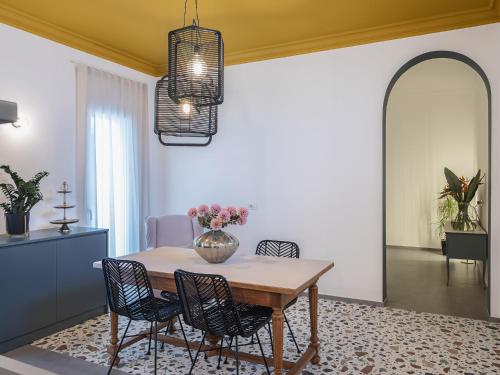 - une table à manger avec des chaises et un vase fleuri dans l'établissement Living u HomeSuites, à Lecce