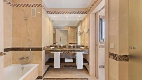 a bathroom with a tub and a large mirror at Puente Romano Marbella in Marbella
