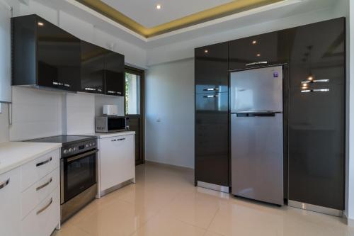 una cocina con electrodomésticos de acero inoxidable y armarios negros en Amazing Holiday Apt with Ocean Views, en Atenas