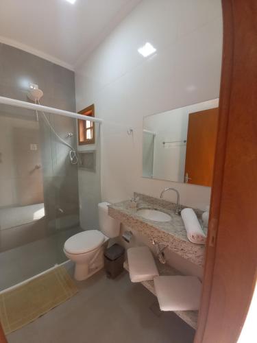 a bathroom with a toilet and a sink and a shower at Chácara Vale Verde in Lindóia