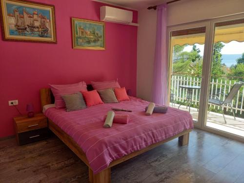 a bedroom with a bed with pink walls and a balcony at Apartments Lorinda in Mošćenička Draga