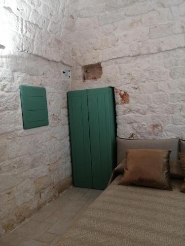 a bedroom with a green door in a stone wall at Trullo Nadia Ostuni in Ostuni