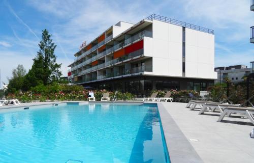 un hôtel avec une piscine en face d'un bâtiment dans l'établissement Appart-Hôtel Mer & Golf City Bordeaux - Bruges, à Bruges