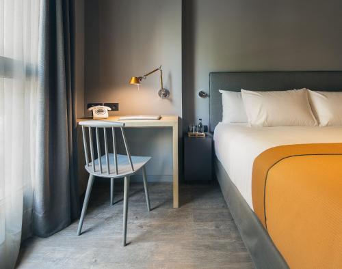 a bedroom with a bed and a chair at Yurbban Trafalgar Hotel in Barcelona