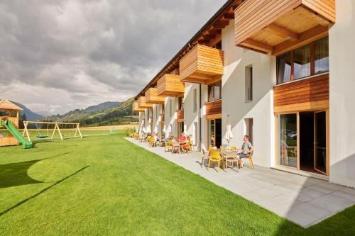 a building with a grass yard with people sitting on chairs at Reka-Ferienanlage Scuol in Scuol