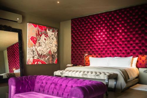 a bedroom with a large bed and a purple couch at Casa Malca in Tulum