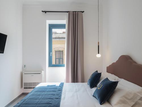 a bedroom with a bed with blue pillows and a window at Living u HomeSuites in Lecce
