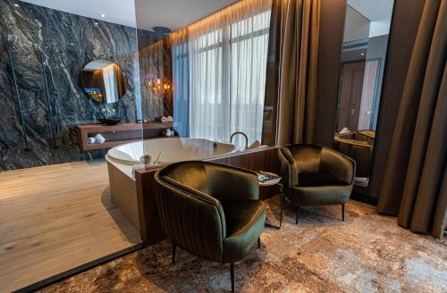 a bathroom with a tub and two chairs at Van Der Valk Hotel Almere in Almere