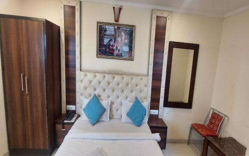a bedroom with a bed with blue pillows and a mirror at Hotel Eden in Jaipur