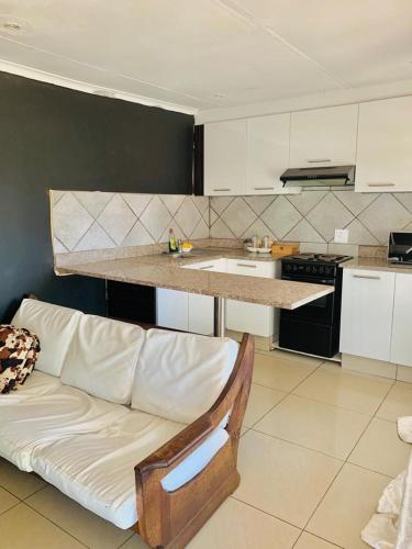 a living room with a couch and a kitchen at Siyaya’s Guest Palace in Jozini
