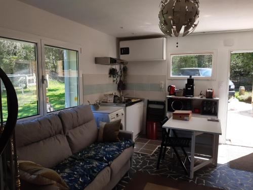 un salon avec un canapé et une cuisine dans l'établissement Appartement en lisière de forêt avec étang, à Scaër